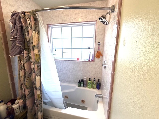 3080 Lee Turner Road Cleveland, TX 77328 - Photo 8 of 48 Primary bathroom features a jetted tub/shower combination, tiled surround, updated showerhead, and a large privacy window for natural light.