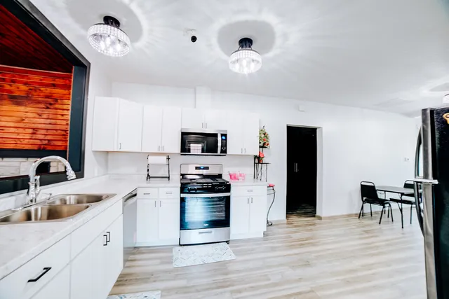 a kitchen with stainless steel appliances kitchen island granite countertop a sink dishwasher a stove and a refrigerator with wooden floor