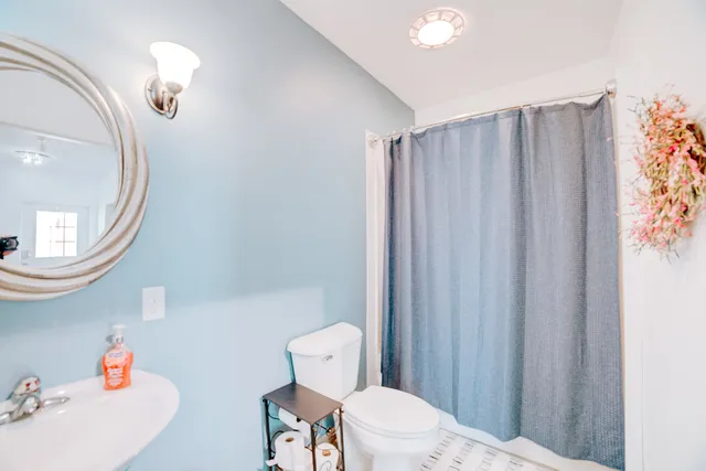 a bathroom with a sink a toilet a mirror and shower curtain