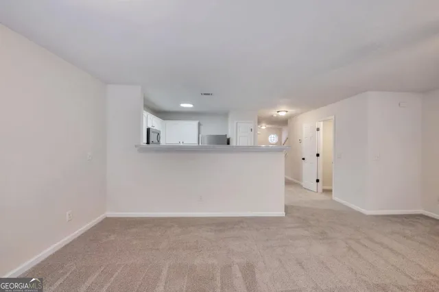 a view of kitchen with refrigerator and white cabinets