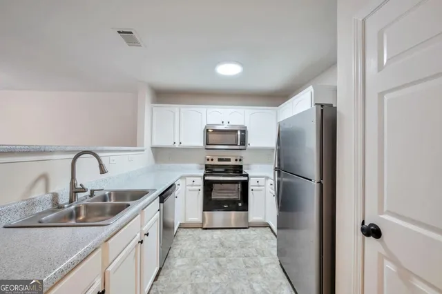 a kitchen with stainless steel appliances a refrigerator sink and microwave