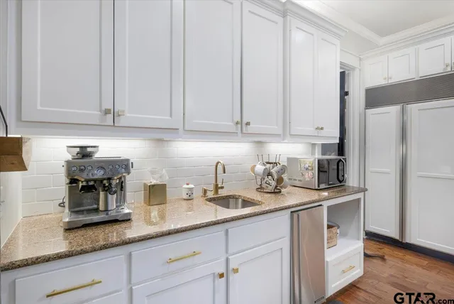 a kitchen with granite countertop stainless steel appliances white cabinets and a sink