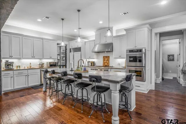 a kitchen with stainless steel appliances kitchen island wooden floors refrigerator dining table and chair