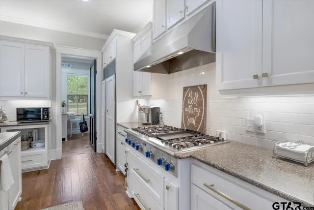 a kitchen with granite countertop a stove and a white cabinets