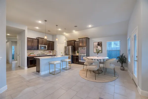 a living room with stainless steel appliances furniture a large window and a view of kitchen