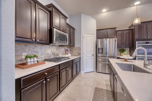 a kitchen with stainless steel appliances granite countertop a refrigerator a sink dishwasher stove and oven