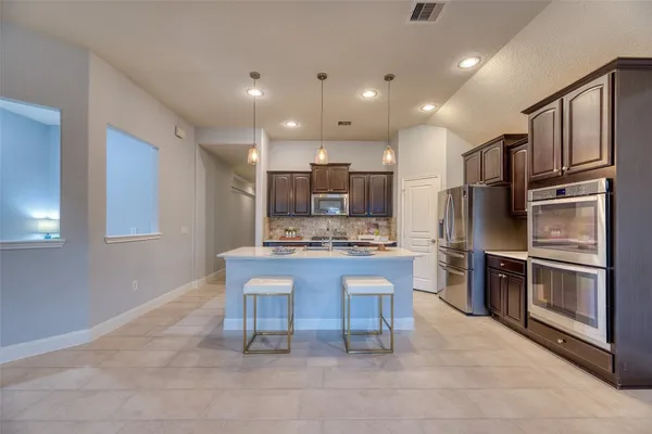 a kitchen with stainless steel appliances kitchen island granite countertop a refrigerator and microwave