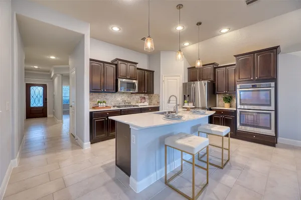 a kitchen with stainless steel appliances kitchen island granite countertop a refrigerator and a stove top oven