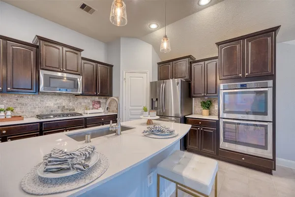 a kitchen with stainless steel appliances kitchen island granite countertop a refrigerator a stove a sink and dishwasher
