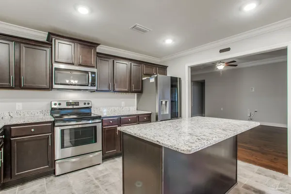 a kitchen with stainless steel appliances granite countertop a kitchen island a stove and a sink