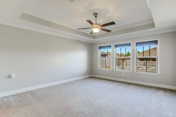 an empty room with chandelier fan and windows