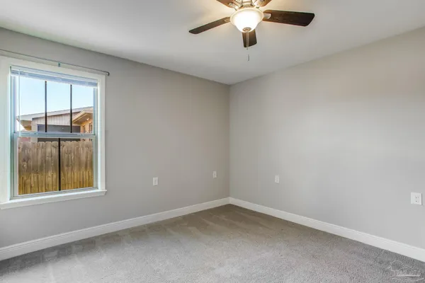 an empty room with windows and fan