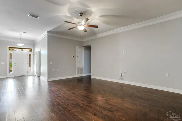 a view of an empty room with wooden floor and a ceiling fan