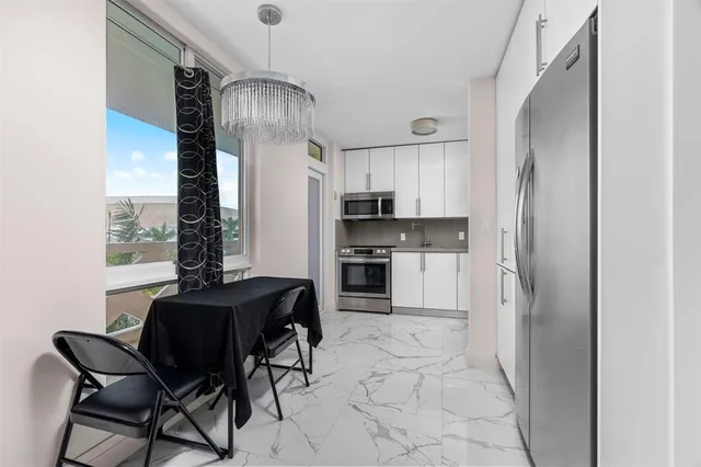 a kitchen with stainless steel appliances granite countertop a refrigerator and a chandelier