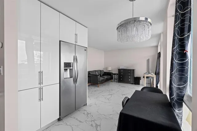 a living room with furniture a flat screen tv and a refrigerator