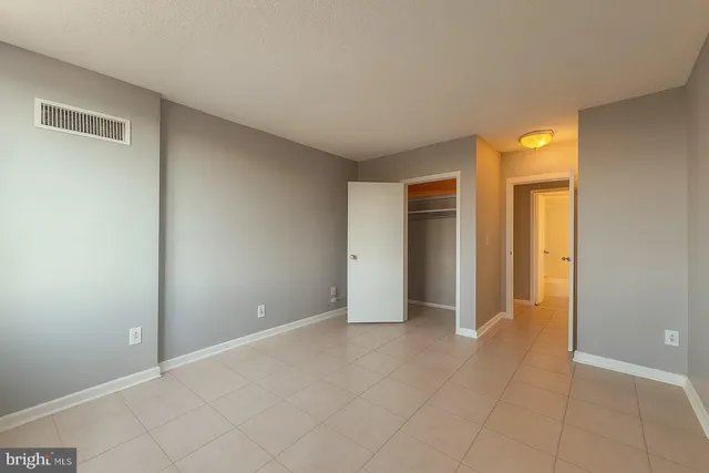 a view of an empty room with closet and a window