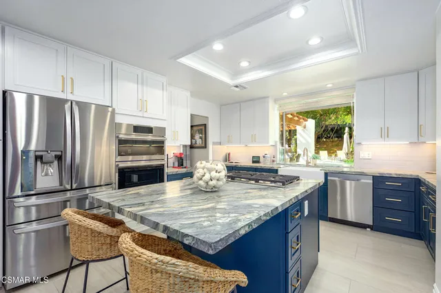 a kitchen with stainless steel appliances granite countertop a table chairs sink refrigerator and microwave