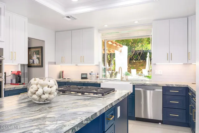a kitchen with kitchen island granite countertop a sink and a stove