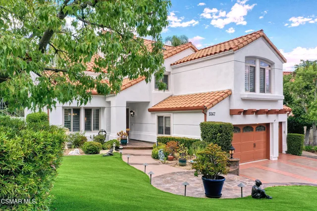 a front view of a house with a yard and potted plants