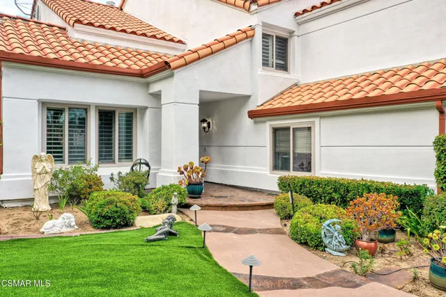 a front view of a house with a yard and potted plants