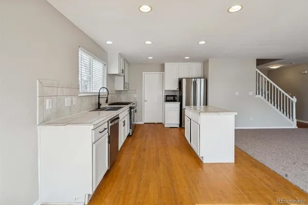 a kitchen with kitchen island granite countertop a sink a counter top space stainless steel appliances and cabinets