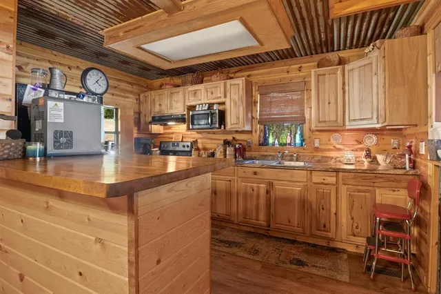 a kitchen with stainless steel appliances granite countertop a stove a sink dishwasher and white cabinets with wooden floor