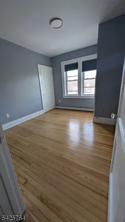a view of empty room with window and wooden floor