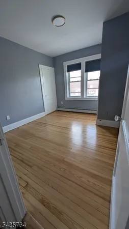 a view of empty room with window and wooden floor
