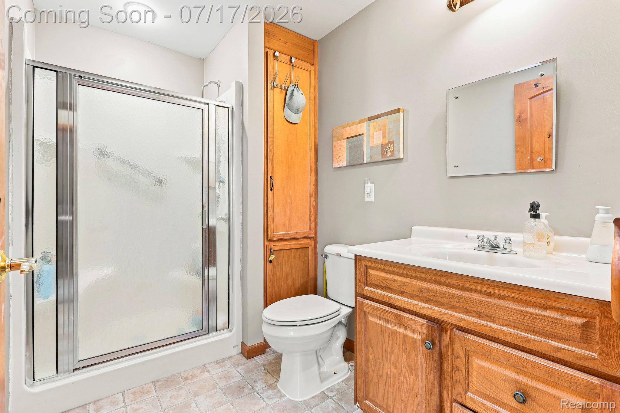 9805 Dolan Road Columbus, MI 48063 - Photo 23 of 39 Bathroom featuring a shower with sliding glass doors, a vanity with wood-finish cabinetry, a built-in linen cabinet, and tile flooring