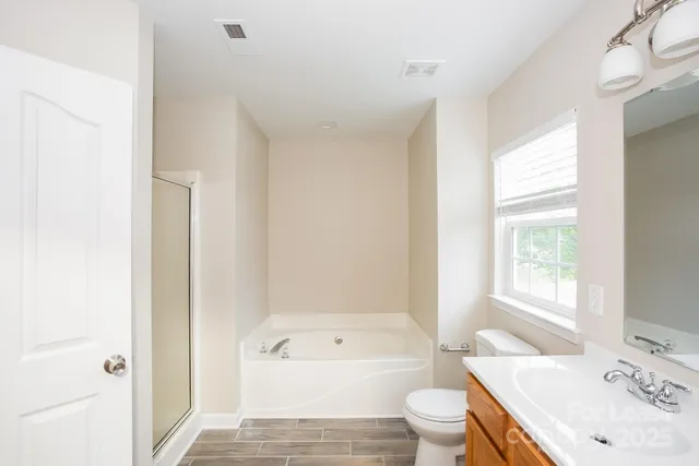 a bathroom with a bathtub shower sink vanity mirror and toilet