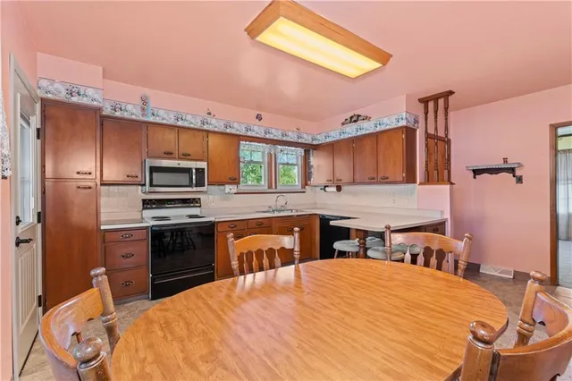 a large kitchen with stainless steel appliances a stove refrigerator sink and cabinets