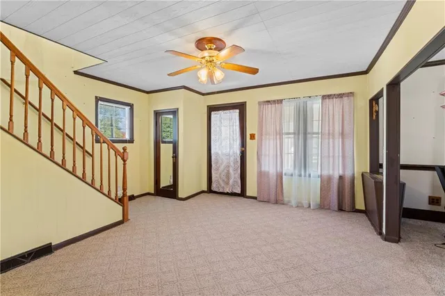 an empty room with ceiling fan and windows