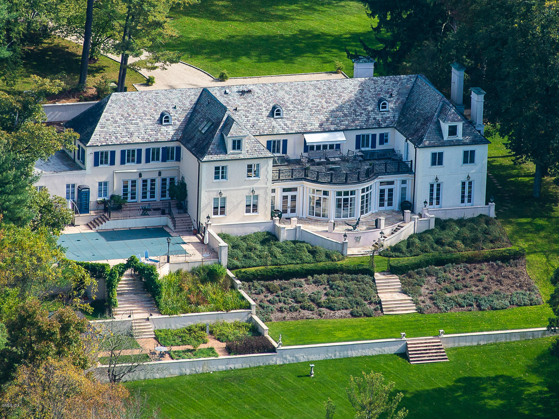 a aerial view of a house next to a big yard and large trees