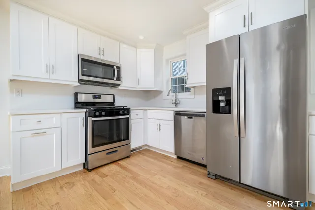 a kitchen with white cabinets and stainless steel appliances