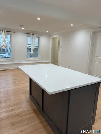 a large kitchen with stainless steel appliances kitchen island a sink dishwasher a refrigerator and a stove with wooden floor