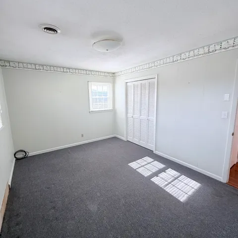 an empty room with wooden floor chandelier fan and windows