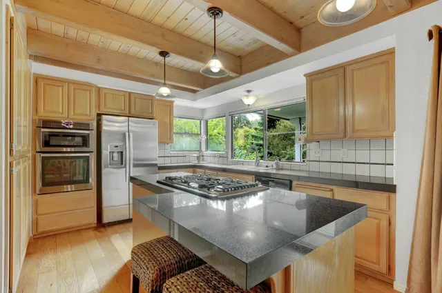 a kitchen with stainless steel appliances granite countertop a sink a stove and a refrigerator