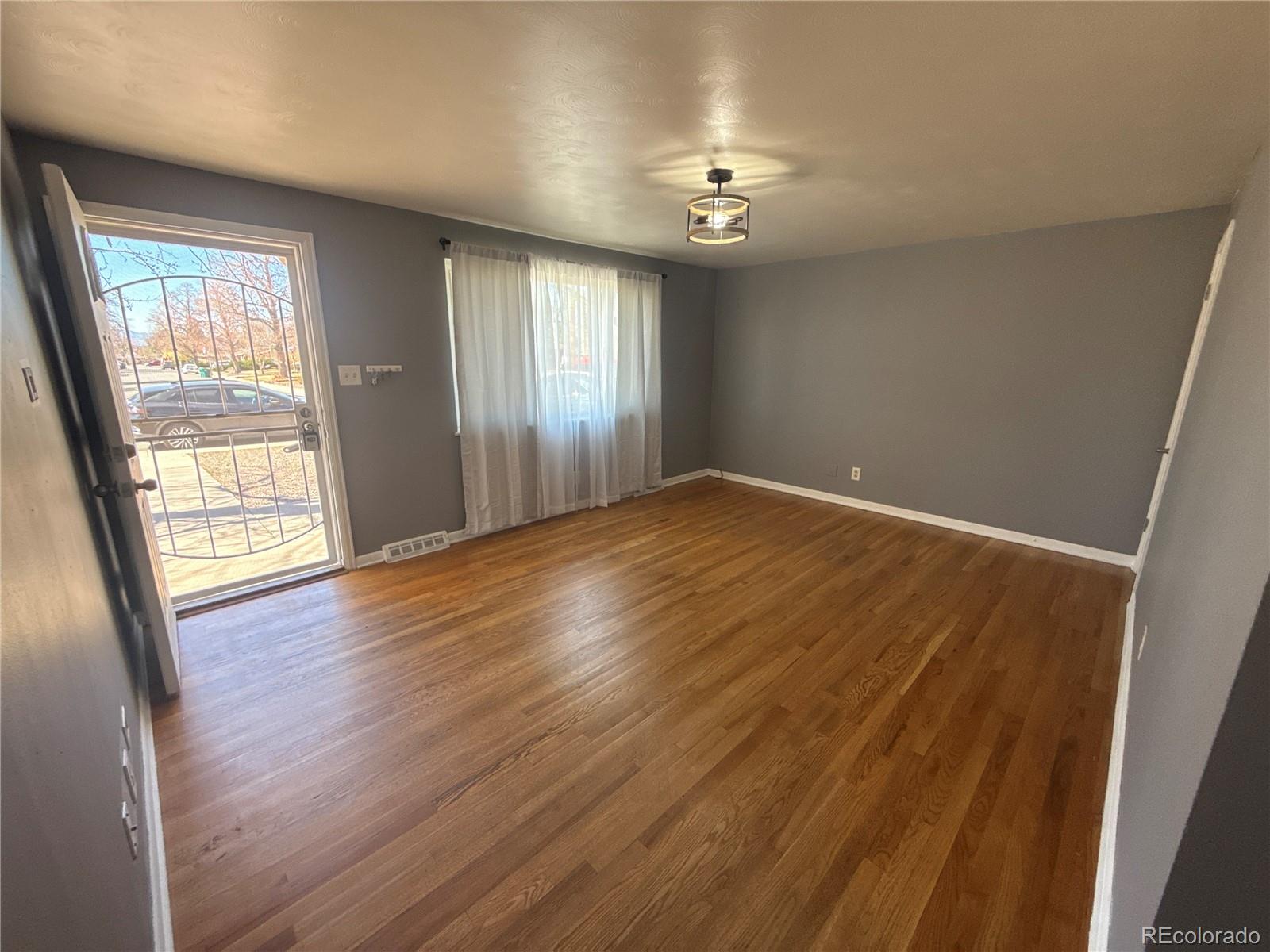 378 South Racine Street Aurora, CO 80012 - Photo 7 of 44 an empty room with wooden floor and windows