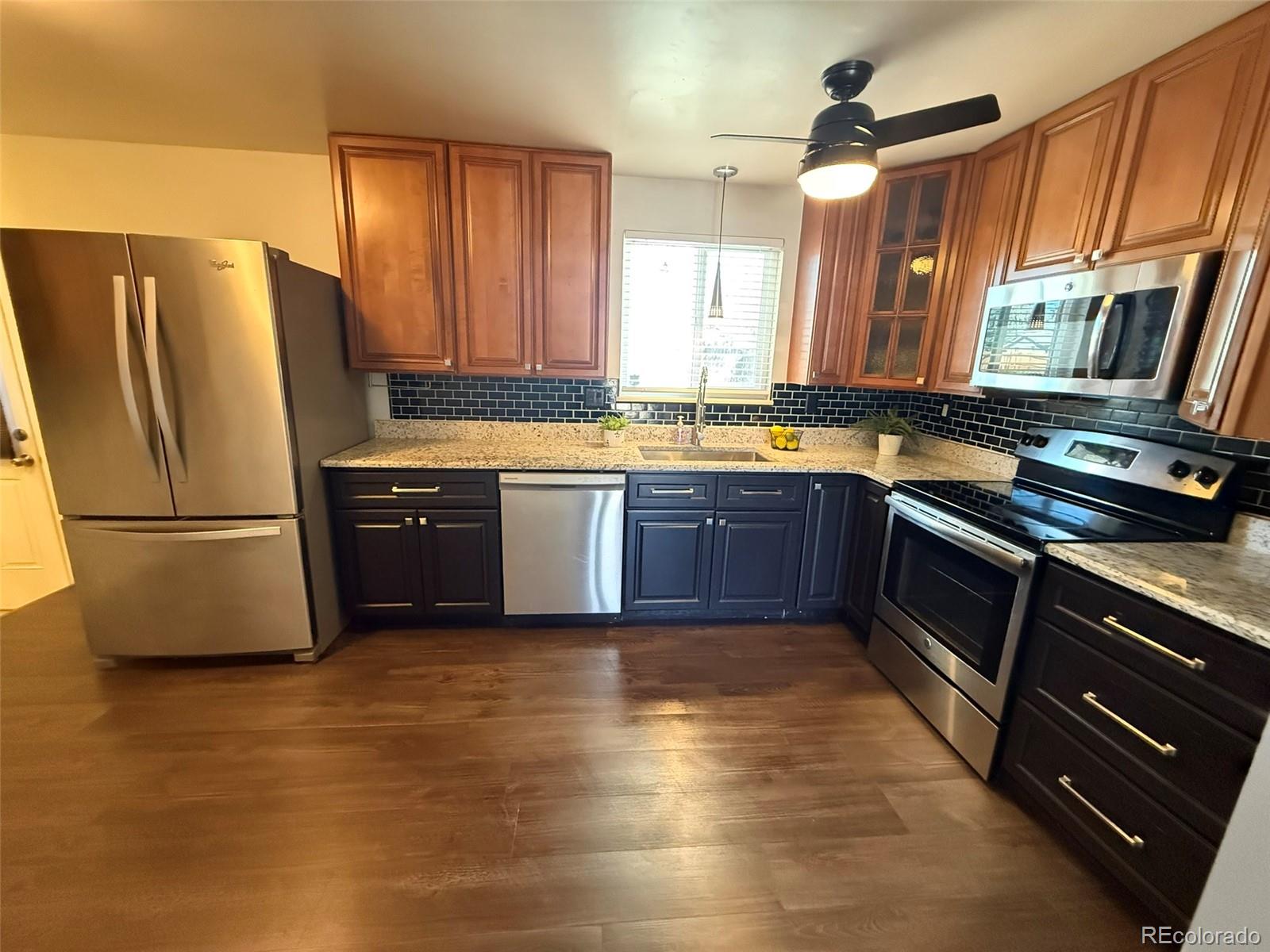 378 South Racine Street Aurora, CO 80012 - Photo 8 of 44 a kitchen with stainless steel appliances granite countertop a refrigerator a sink dishwasher a stove with wooden cabinets and floor