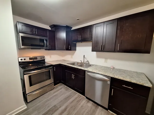 a kitchen with stainless steel appliances granite countertop wooden cabinets and a stove top oven