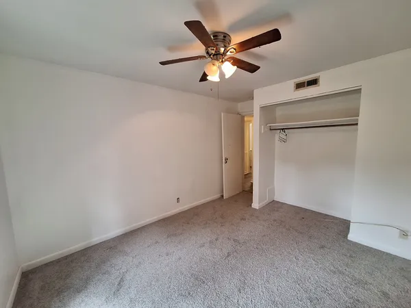 an empty room with closet and a ceiling fan