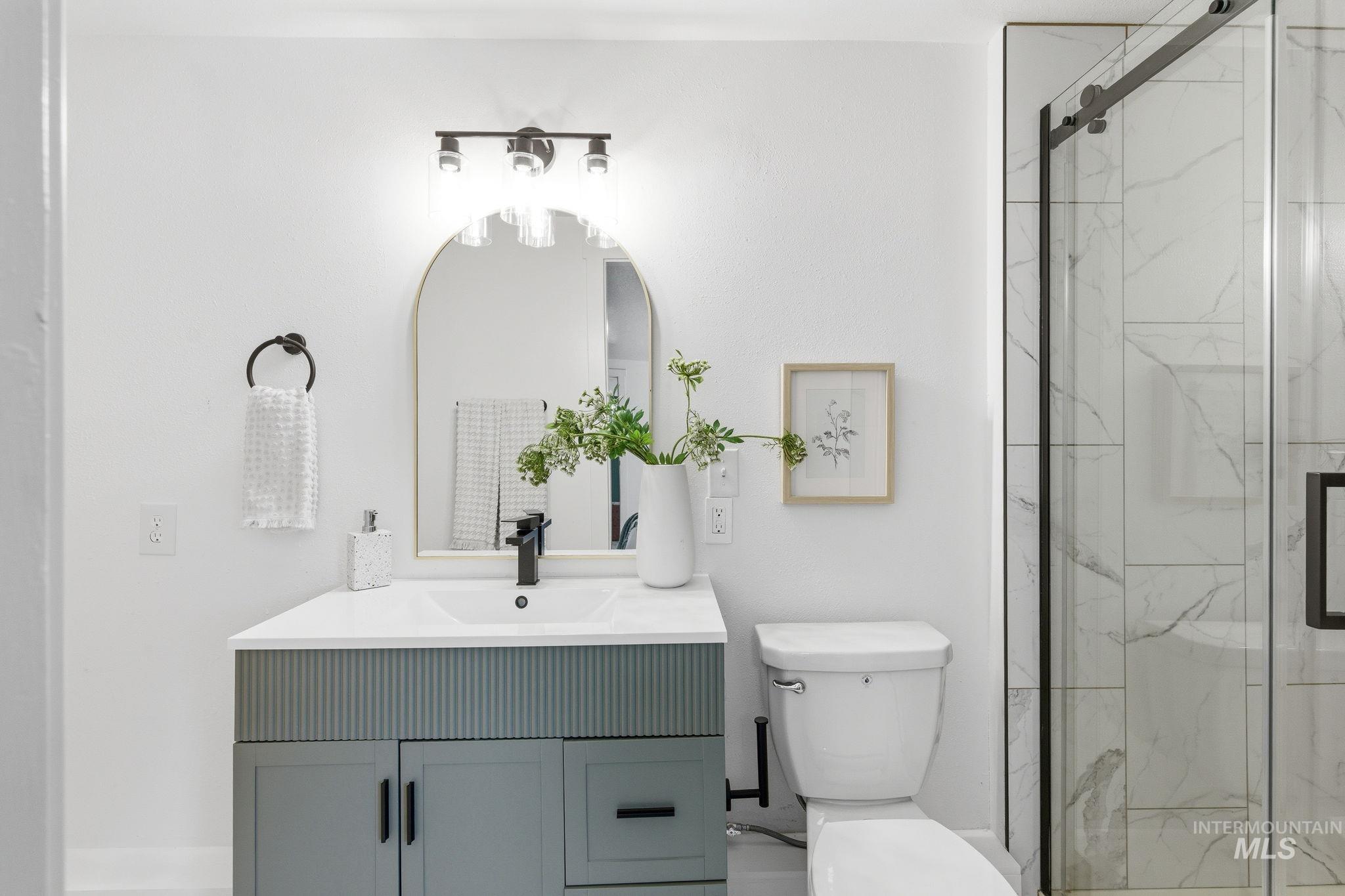 2224 Rachel Circle Boise, ID 83706 - Photo 35 of 50 Modern bathroom vanity with reeded paneling and white countertop, complemented by a black-framed arched mirror