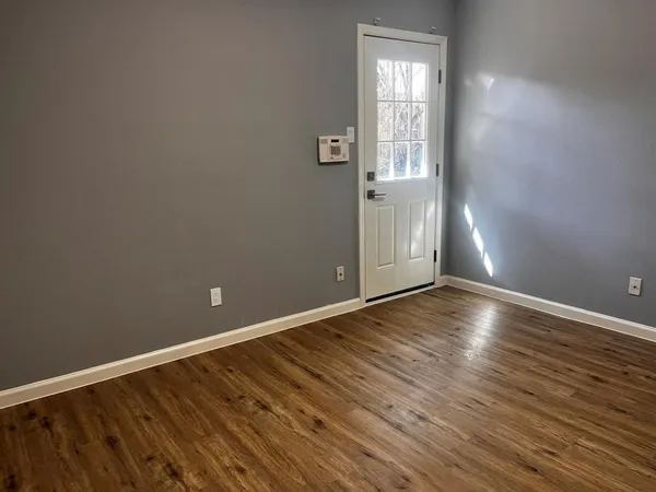 a view of an empty room with wooden floor and a window