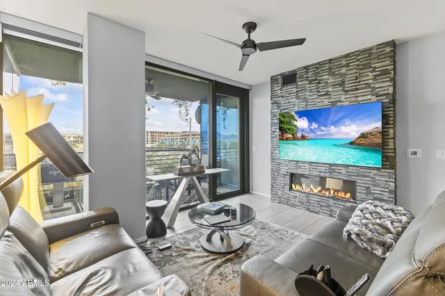 a living room with furniture a flat screen tv and a floor to ceiling window