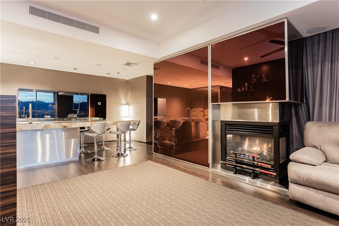 4381 West Flamingo Road, Unit 53321 Las Vegas, NV 89103 - Photo 13 of 41 Living room featuring a lit fireplace, wood finished floors, and recessed lighting