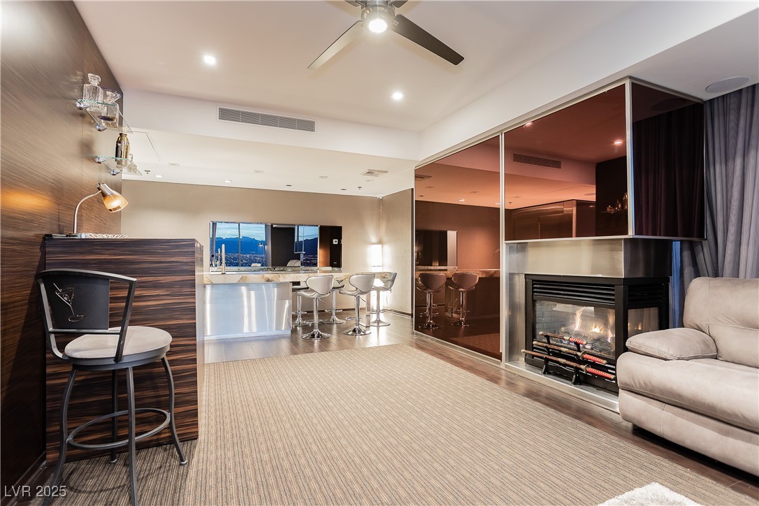 4381 West Flamingo Road, Unit 53321 Las Vegas, NV 89103 - Photo 14 of 41 Living area with a multi sided fireplace, recessed lighting, ceiling fan, and wood finished floors