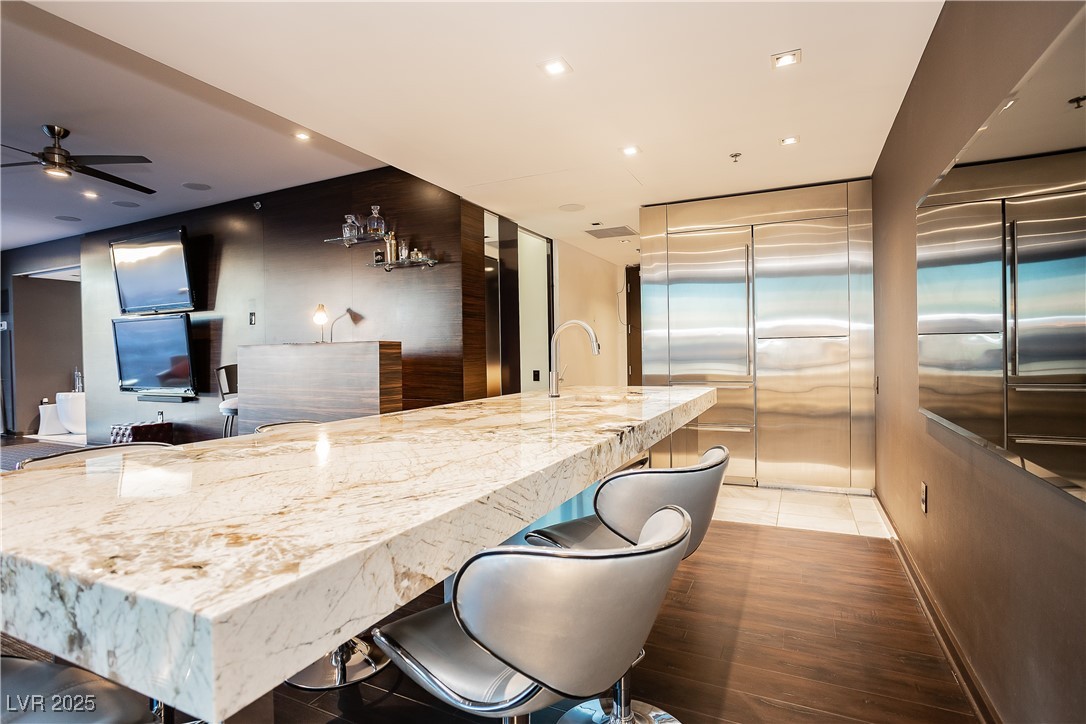 4381 West Flamingo Road, Unit 53321 Las Vegas, NV 89103 - Photo 9 of 41 Kitchen with a kitchen bar, light stone counters, recessed lighting, stainless steel built in fridge, and ceiling fan