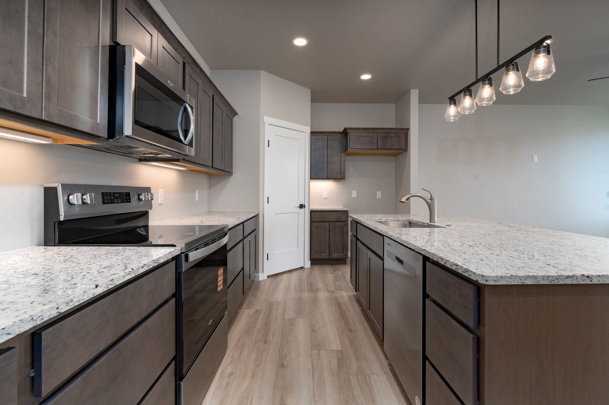 1750 Caliper Way Fruita, CO 81521 - Photo 18 of 19 a kitchen with stainless steel appliances granite countertop a kitchen island a stove a sink and a microwave