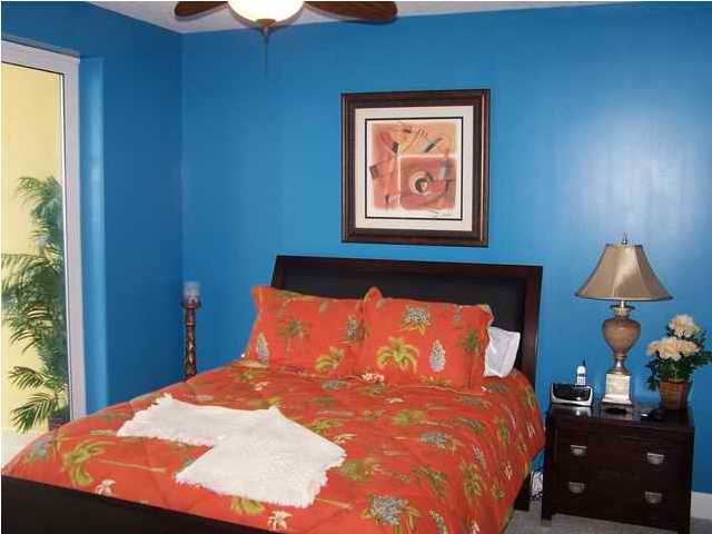 10519 Front Beach Road, Unit 2201 Panama City Beach, FL 32408 - Photo 6 of 10 a bedroom with a bed and a lamp on dresser