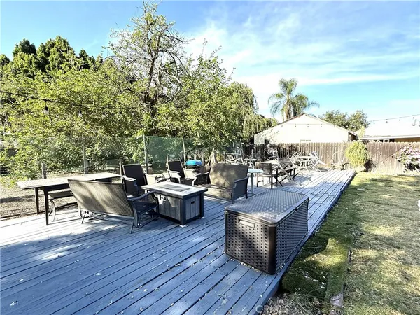 a view of a patio with couches table and chairs under an umbrella with wooden floor